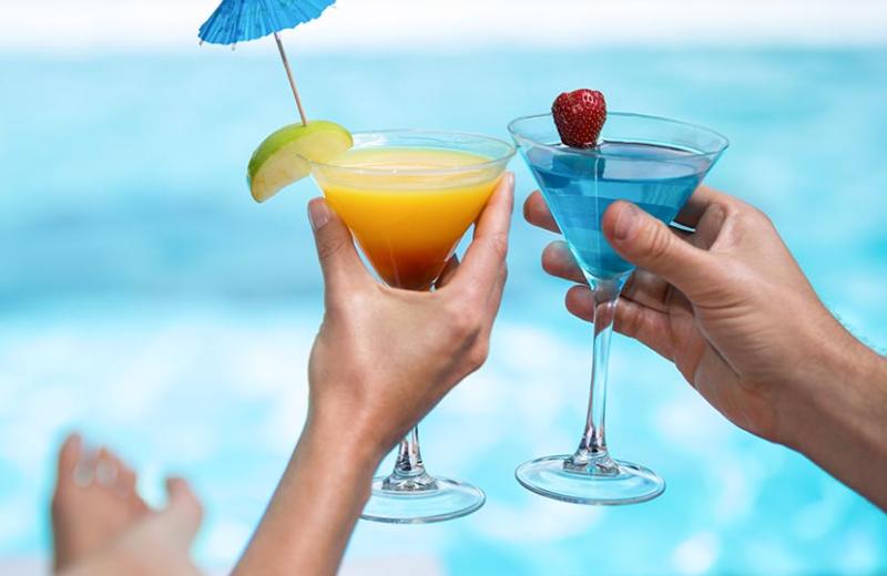 Due cocktail colorati con frutta decorativa vicino a una piscina.